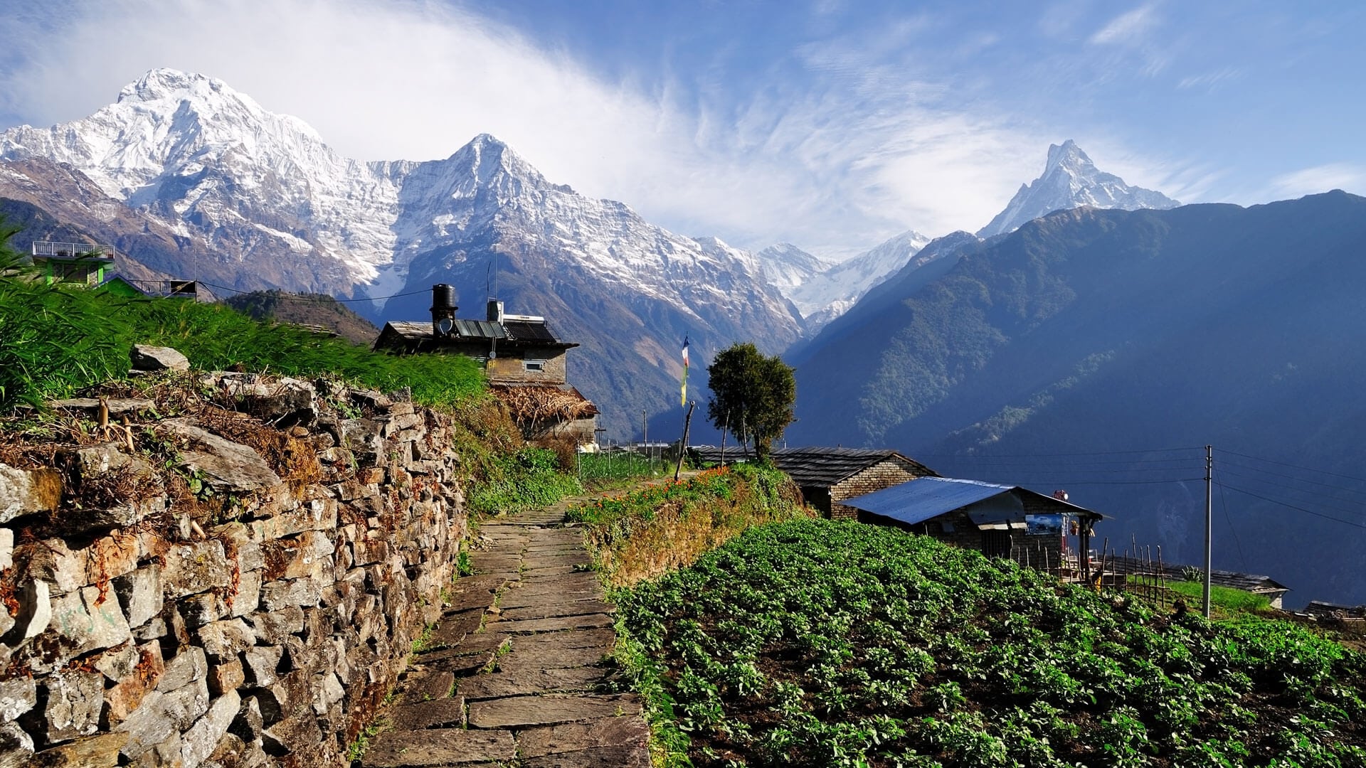 Mountain landscape with stone wall, pathway, and traditional houses in Nepal mountain village.
