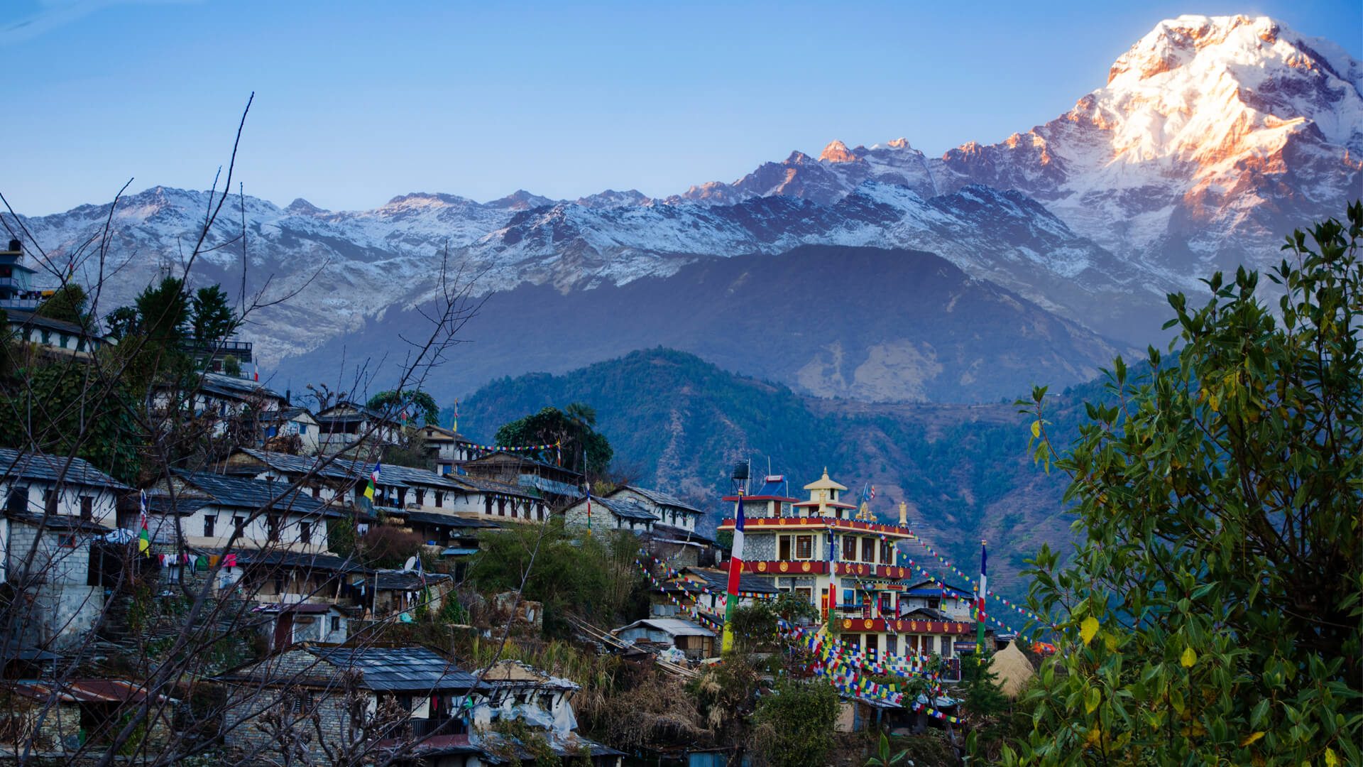 Nepali Mountain village with colorful buildings against a backdrop of snow-capped Himalayan mountains.
