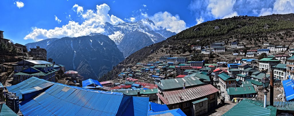 Village with blue roofs and snow-capped mountains under a blue sky. A panoramic view of Namche Bazar